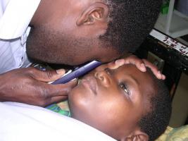 A young African child being examined with one of the Grange's 'Optyse' ophthalmoscopes